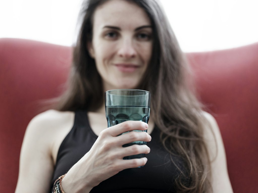 Woman holding a glass of water, representing healthy preconception health habits