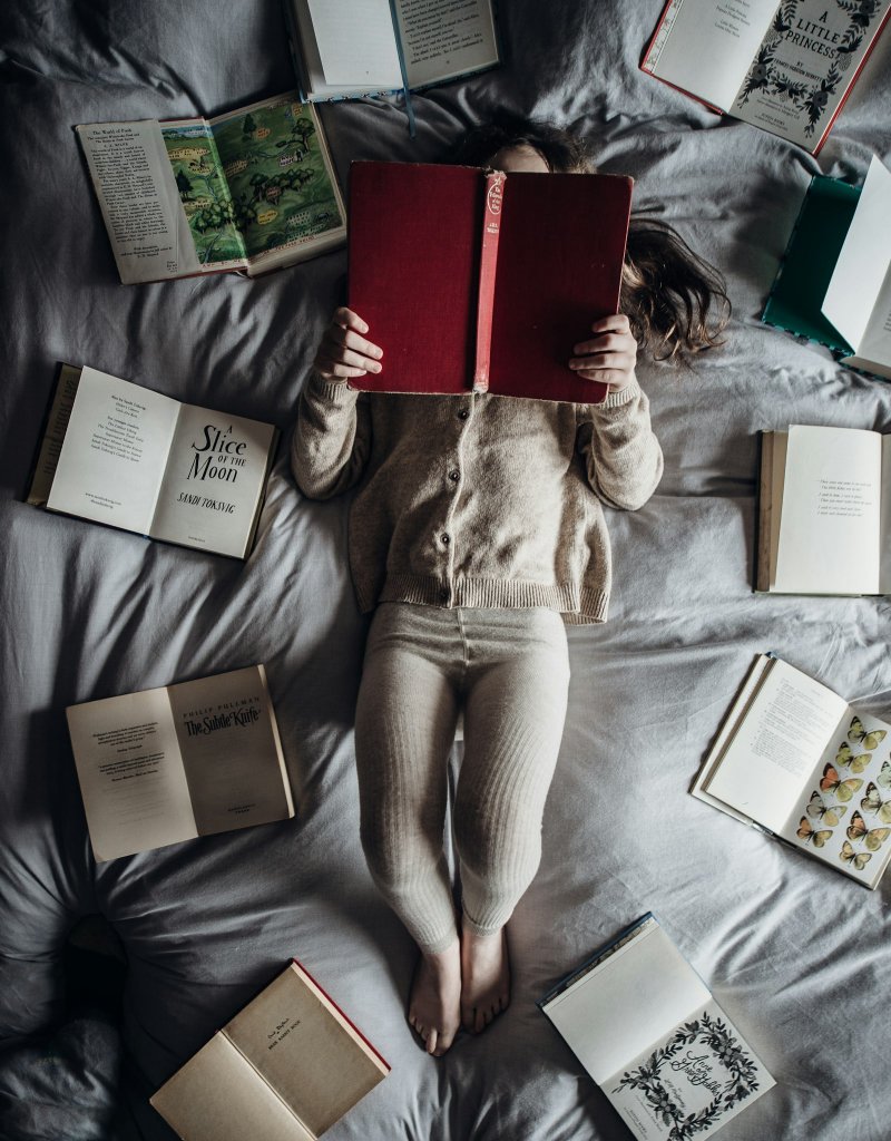 Bedtime Routine for Kids: Calm Evenings That Help Sleep 2 Little girl lying on a bed with books, a calm bedtime routine for kids