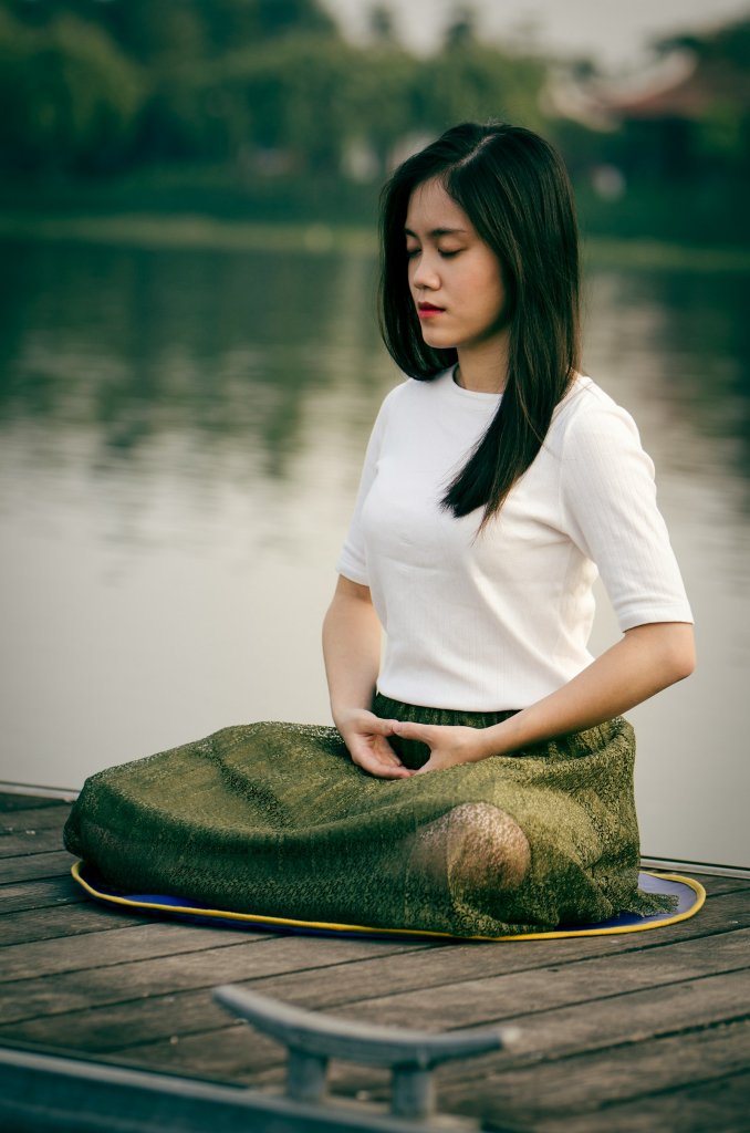 Breathing Exercises for Stress: 4 Simple Techniques 2 Woman practicing breathing exercises for stress while seated on a wooden dock