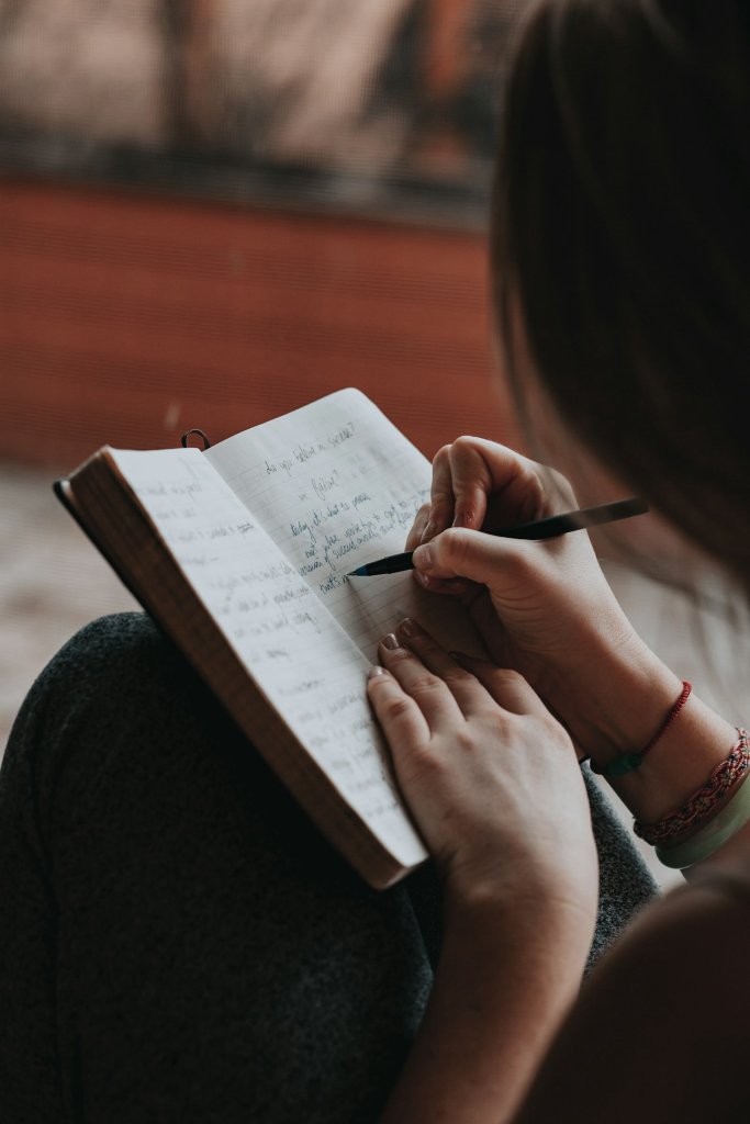 Woman writing in a notebook, taking quiet time for burnout recovery
