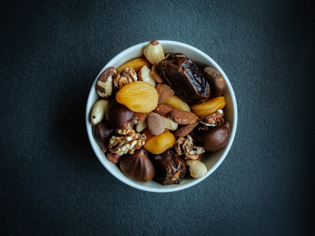 White bowl of nuts on a table, a filling snack among foods that keep you full
