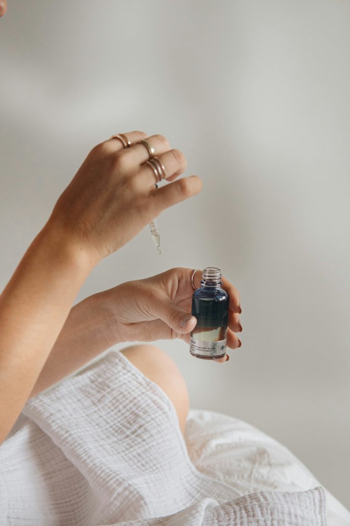Hand holding a glass dropper bottle of hyaluronic acid serum for skin